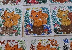 Prace plastyczne na stoliku - wiewiórki pokolorowane pastelami.