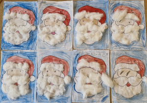 Prace dzieci na stoliku - głowa Mikołaja z pokolorowaną na czerwono czapką i wyklejonymi watą brodą i wąsami.