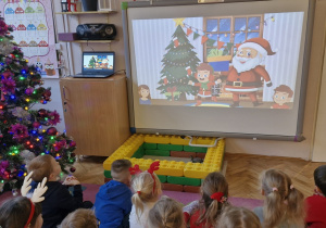 Dzieci na tablicy oglądają film o Świętym Mikołaju.