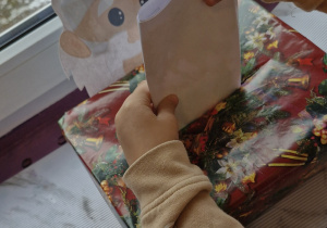 Dziecko wrzuca list do świątecznej skrzynki pocztowej.