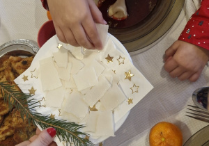 Dziecko z talerza bierze opłatek.