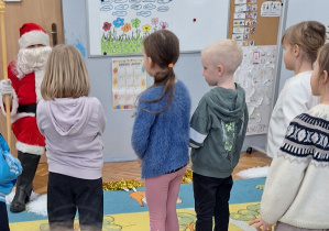 Dzieci stoją przed Świętym Mikołajem.