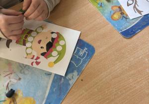 Dzieci przy stoliku wylepiają postacie z plasteliny- skrzata.