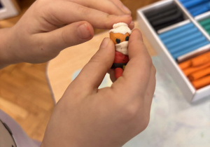 Dziecko lepi przy stoliku Mikołaja z plasteliny.