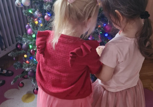 Dziewczynki ubierają choinkę.