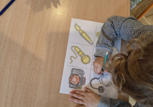 Dziewczynka koloruje różne przedmioty związane z zawodami.