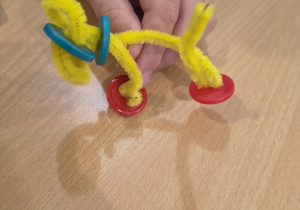 Dziecko uformowało pieska z drucików i guzików.