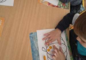 Dzieci pracują przy stoliku - wyklejają plasteliną dynie.