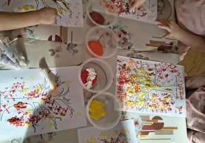 Dzieci malują jesienne drzewa.