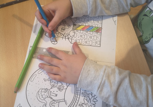 Dziecko koloruje świąteczne karty pracy.