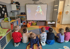 Dzieci oglądają film edukacyjny o Świętym Mikołaju.