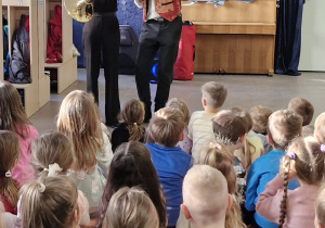 Kobieta gra na instrumencie, mężczyzna obok niej śpiewa.