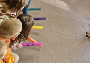 Dzieci grają na kolorowych rurkach.