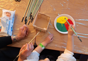 Dziewczynka z babcią maluje farbami doniczkę