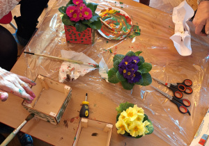 Dzieci z babciami malują drewniane doniczki