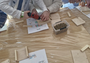 Chłopiec z wykorzystaniem wkrętarki wkręca śrubki