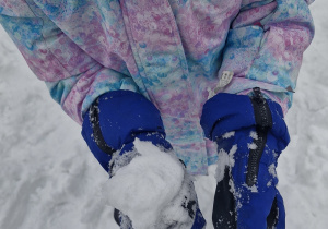 Dziewczynka na rączce trzyma śnieżkę.
