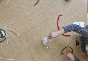 Dzieci pracują przy stoliku - wykonują bałwanki z płatków kosmetycznych.