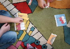 Dzieci na dywanie układają puzzle przedstawiające symbole narodowe.