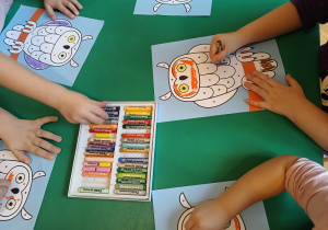 Dzieci kolorują według kodu obrazki przedstawiające sowy.