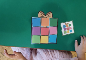 Praca dziecka – kolorowe kwadraty ułożone na obrazku prezentu według kodu.