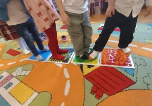 Dzieci stoją na płytkach sensorycznych.