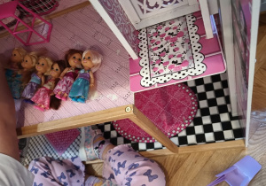 Dziecko układa w domku laleczki