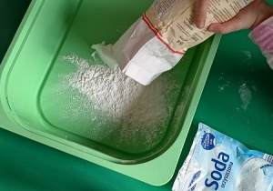 Dziecko wsypuje do pojemnika mąkę.