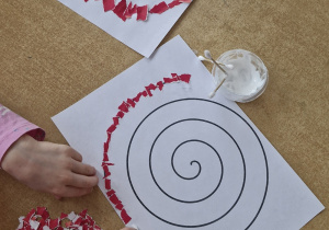 Dzieci wyklejają szlaczki kolorowym papierem.