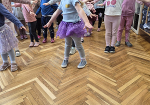 Dziewczynki ze wszystkich grup na scenie powtarzają ruchy za prowadzącą.