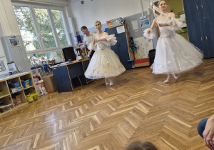 Kobiety w strojach wróżek tańczą na scenie.