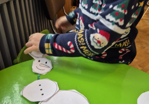 Dziecko tworzy bałwanka z papieru.