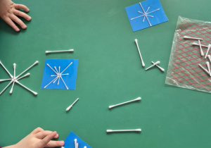 Dzieci układają z patyczków śnieżki według podanego wzoru.