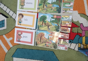 Na dywanie rozłożone ilustracje przedstawiające różne pory roku.