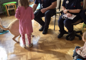 Dziewczynka stoi obok psa i funkcjonariuszy Straży Miejskiej.