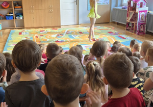 Przedszkolaki patrzą na tańczącą dziewczynkę.