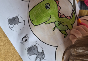 Dziecko wycina dinozaura w jaju po linii.