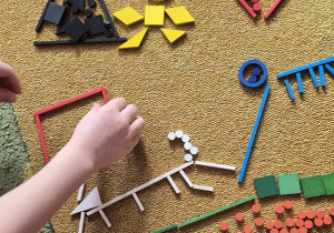 Dzieci układają świat dinozaurów z darów zabawy Froebla.