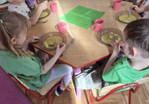 Dzieci przy posiłku ubrane na zielono.