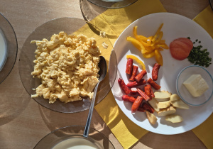 Na stole jajecznica oraz warzywa ułożone na talerzu.