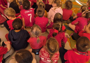 Dzieci na dywanie ubrane na czerwono.