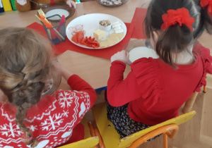 Dzieci ubrane na czerwone jedzą posiłek.