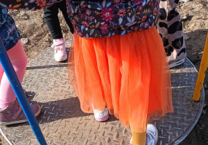 Dziewczynka w pomarańczowej spódniczce na karuzeli.