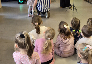 Dzieci stoją przy kobiecie z instrumentem.