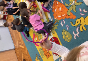 Dzieci na dywanie układają litery T z drucików kreatywnych.