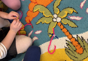 Na dywanie ułożona litera T z drucików kreatywnych.