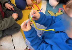 Dziecko tworzy literę T z drucików kreatywnych.