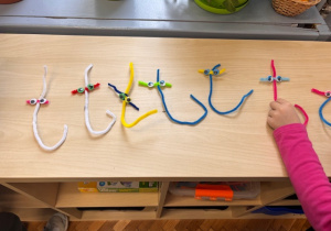 Litery T prezentowane na półce , oglądane przez dzieci.