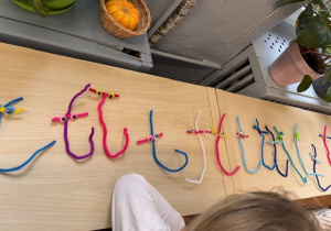 Na półce litery T wykonane przez dzieci z drucików kreatywnych.