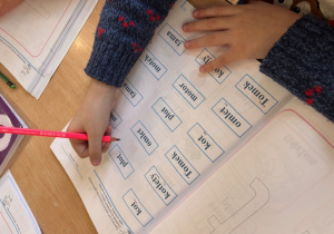 Dziecko przy stoliku uzupełnia ćwiczenia dotyczące utrwalenia litery T.